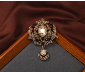 Macro view of vintage palace style hollow brooch with amber crystals and a teardrop pendant