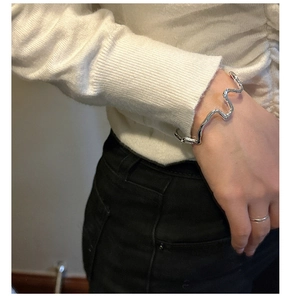 Detailed close-up of a silver irregular wave-textured cuff bracelet worn by a model
