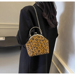 Close-up of vintage leopard print shell bag with golden metal handle and chain strap