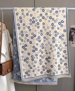 Detail of blue and beige floral scarf with fringe edges hanging in a closet