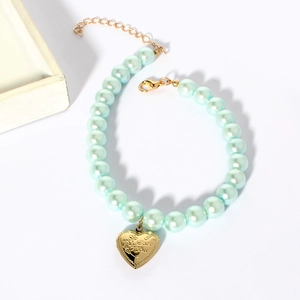 Detail of light blue pearl pet collar featuring a gold heart pendant with I Love You engraving