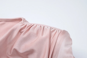 Detail of pink satin dress showing elegant ruched shoulder design and silky fabric texture