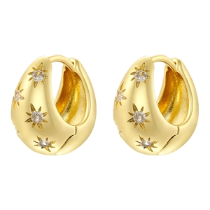Detail of gold huggie hoop earrings with starburst patterns and sparkling gemstones