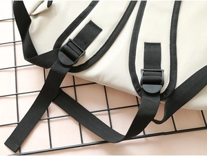 Detail of black nylon shoulder strap with adjustable buckle on beige canvas backpack