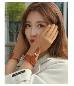 Detail of khaki suede gloves with brown leather strap and metal buckle on the wrist