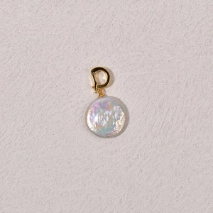Macro shot of an iridescent flat baroque pearl pendant with a golden spring clasp