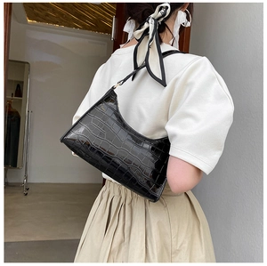 Side view of a black crocodile pattern shoulder bag on a model for a stylish look