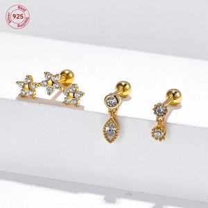 Macro shot of gold s925 silver stud earrings with zircon stars and flower charms