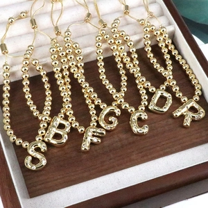 Detail of gold beaded bracelets with sparkling cubic zirconia alphabet charms in a jewelry box