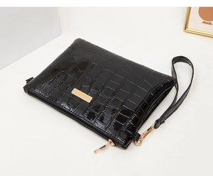 Detail of black stone pattern crossbody bag featuring glossy leather and gold zipper