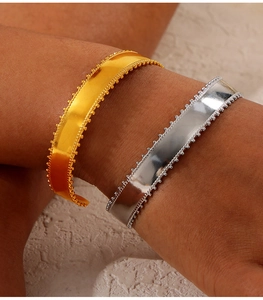 Macro detail of polished gold and silver cuff bracelets with fine beaded texture edges