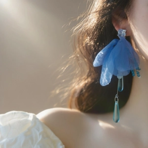 Primer plano de pendientes de flores de gasa azul con circonitas en una modelo