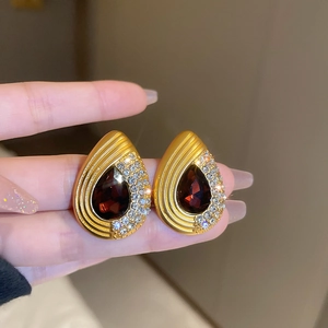Detail of luxury water drop earrings with deep red pear-cut stone and diamond accents