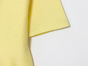 Detail van lichtgeel fijngebreid materiaal met hoogwaardige stiksels en textuur