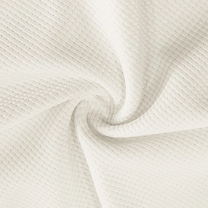 Detailed macro shot of white waffle weave fabric texture with soft ripples and folds