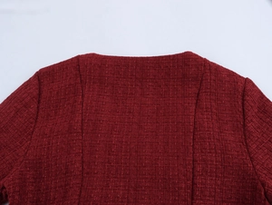 Detail view of the deep burgundy tweed fabric texture and back shoulder seam on the dress