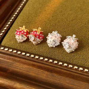Close-up of gold-plated strawberry earrings with red and pink enamel and zircon inlay