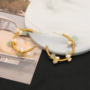 Detail of handmade gold wire-wrapped hoop earrings with white pearls and green stones