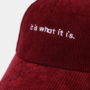 Dettaglio del cappellino da baseball in velluto bordeaux con ricamo bianco artigianale
