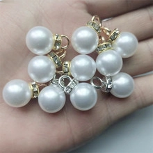 Detailed macro view of 16mm white faux pearl pendants with crystal metal hoop bail caps