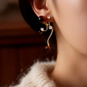 Vintage golden earrings with brown tiger eye stones and zircon accents on model