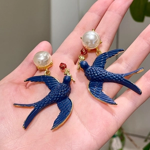 Detail of vintage bird earrings with blue enamel, gold edges and white pearl
