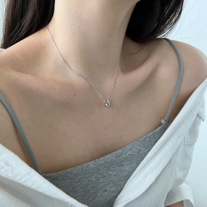 Close-up of minimalist polished silver teardrop pendant necklace on woman's neckline