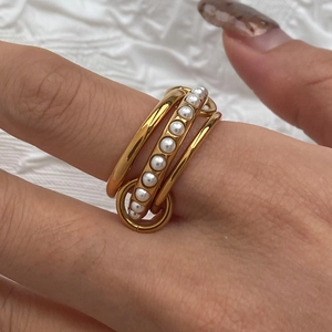 Detail of 18K gold multi-layer stacking ring with linear pearl inlay on female hand