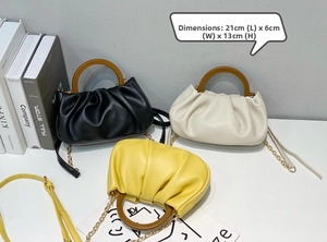 Detailed view of pleated saddle bags in black, beige and yellow with wooden handles
