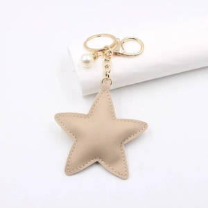 Detailed view of beige Saffiano leather star keychain with gold hardware and pearl bead