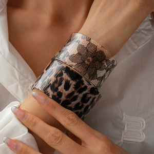 Detail of wide acrylic bangles with leopard print and black lace patterns on model's wrist