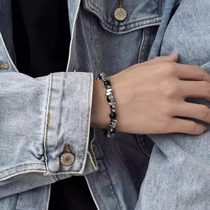 Minimalist black beaded bracelet with irregular silver titanium steel accents on male wrist