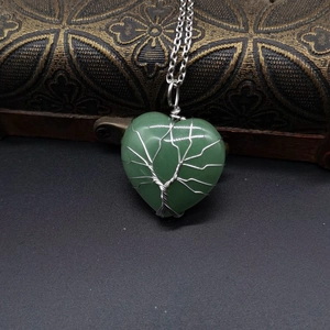 Close-up of tree of life wire-wrapped heart green stone pendant on wooden box