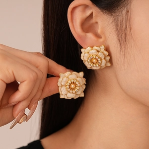 Detail of large gold-edged white flower earrings with multi-layer petals worn by model