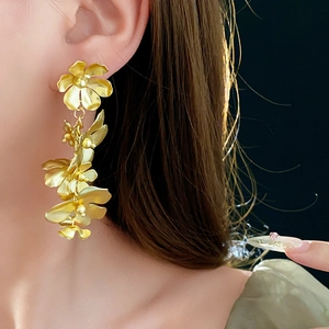 Gros plan de boucles d'oreilles fleurs dorées à pompons sur un mannequin de profil