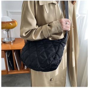 Detailed view of the black quilted nylon crossbody bag shown in a lifestyle indoor setting