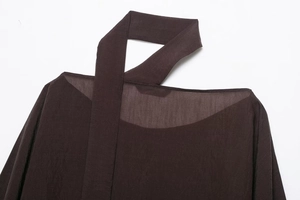 Close-up of asymmetrical neckline and sheer fabric detail on dark coffee cape top