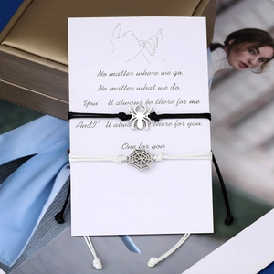 Detail of spider and web charm couple bracelets on a sentimental message card