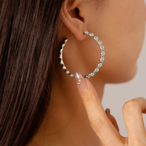 Close-up of a silver hoop earring with turquoise beads on a model's ear