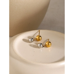 Vue détaillée des boucles d'oreilles boules bicolores or et argent sur céramique