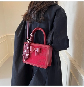 Macro shot of red bridal handbag with floral texture, bow detail and silk scarf handle