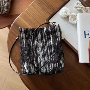 Detail shot of mini crossbody bag in black and white tweed with simple wish label