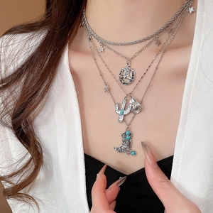 Macro shot of silver layered necklace with western cowboy boot, hat and cactus charms