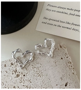 Dettaglio di orecchini a cuore in argento S925 con trama a lava su superficie in pietra
