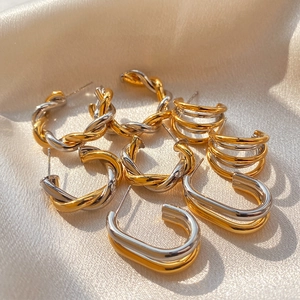 Modern mixed metal hoop earrings in gold and silver tones on white silk fabric