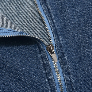 Détail de la fermeture éclair en métal et coutures du tissu denim sur le body bleu
