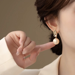 Elegante goldene Perlenohrringe an einem Model in einer professionellen Studioumgebung