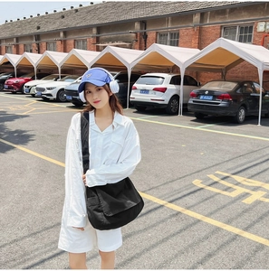 Outdoor model display of a black washed canvas crossbody bag with slouchy lazy style