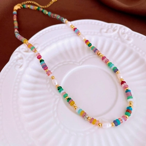 Détail d'un bracelet en pierres naturelles et perles sur un plateau en céramique blanche
