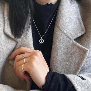 925 silver twisted heart necklace and stacked rings set on model with black turtleneck
